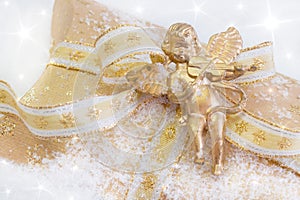 Close up of golden present box with angel playing violin for christmas on snowy background