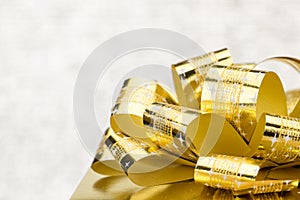 Close up Golden present box with big bow at bokeh white blur background
