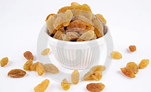 Close-up of golden raisins dry grapes in a ceramic bowl over white background