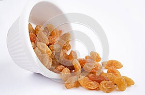 Close-up of golden raisins dry grapes in a white ceramic bowl over white background
