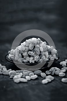 Close up of Golden raisins or Kishmish in a bowl on wooden surface.