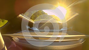 CLOSE UP: Golden sunbeams shine through rear window of car driving down highway.