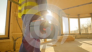 CLOSE UP: Golden sunbeams shine on worker coming to work in prefabricated house.