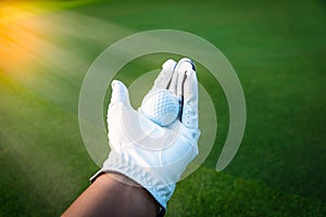 Close up golf ball in golf glove hand with green grass