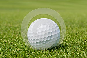 Close up Golf ball on grass with blurred green course backgr