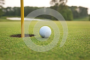 Close up of golf ball on a green near hole with pin