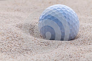 Close up golf ball in sand bunker.