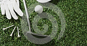 Close up of golf club, ball, glove and peaked cap on grass, copy space, slow motion