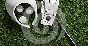 Close up of golf club, balls, glove and peaked cap on grass, copy space, slow motion