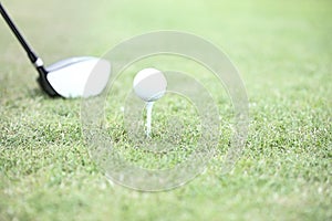 Close-up of golf club and tee with ball on grass