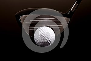 A close-up of a golf driver and golf ball on black