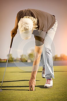 Close up of golf player picking up ball.