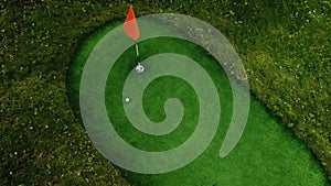 Close-up of golfer using putter to sink short putt into hole