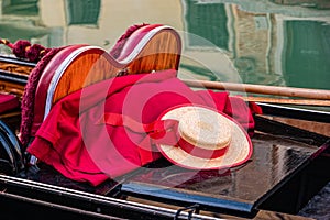 A close up of a gondola with oars, gondolier hat and red blanket in Venice, Italy