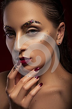 Close up of a gorgeous a bit brutal woman with creative fashion make up: glitters and glamour shine. look