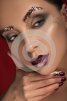 Close up of a gorgeous a bit brutal woman with creative fashion make up: glitters and glamour shine. look