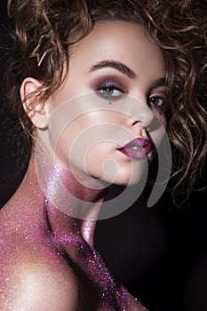 Close up of a gorgeous woman with creative fashion make up: glitters and glamour shine. Curly evening hairstyle. look