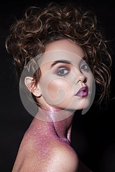 Close up of a gorgeous woman with creative fashion make up: glitters and glamour shine. Curly evening hairstyle. look