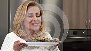Close up of a gorgeous woman smelling delicious vegetarian salad