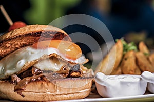 Close up on a gourmet burger with eggs and potato fries photo