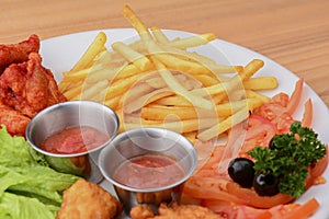Close up gourmet main dish for dinner with crispy fried chicken, french fries and veggies on white plate.
