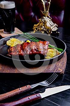 Close up Gourmet Main Dish with Grilled Pork Rib and Fried Potatoes on Black pan. Served on Wooden Board