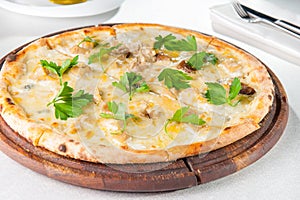Close up gourmet pizza with gorgonzola and porcini white mushrooms decorated with parsley leaves on the wooden board