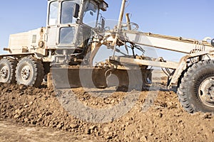 a close up grader scoop dig the dirt on summer day, making a parapet