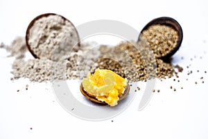 Close up of grain of pearl millet or bajra or bajri in a clay bowl with its flour and jaggery in a small glass plate ingredients