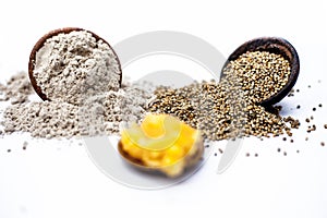 Close up of grain of pearl millet or bajra or bajri in a clay bowl with its flour and jaggery in a small glass plate ingredients