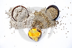 Close up of grain of pearl millet or bajra or bajri in a clay bowl with its flour and jaggery in a small glass plate ingredients