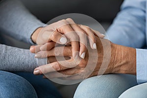 Close up granddaughter comforting grandmother, holding hands, expressing love