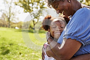 Close Up Of Granddaughter Hugging Grandmother In Park photo