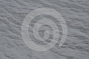 Close up of gray snow background. Snow covered ground on a frosty winter day. The concept of colds and blizzards. Frozen river or