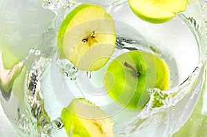 Close up green apples falling in water with splash.