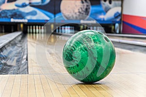 Close-up of green bowling ball against background of empty lanes in bowling alley