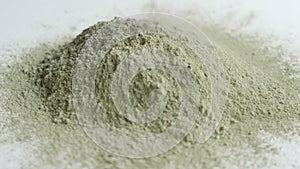 Close up green clay powder rotates on white background