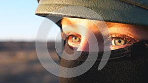 Close up green eyes of female ukrainian army soldier looking at sunset. Sight of young military woman in helmet and