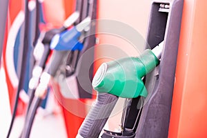 Close up green fuel nozzle on tank of gas station in commercial gas station to filling power oil energy into car for