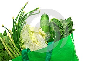 Close up a green grocery bag of mixed organic green vegetables