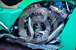 Close up of a green motorcycle with a shiny chrome engine and mirror-like reflections