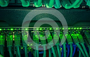 Close up of green network cables connected to switch glowing in the dark