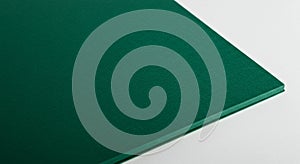 Close-up of a green paper stack placed on a white surface. The paper's texture is