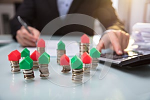 Close-up Of Green And Red House Model On Stacked Coins