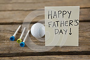 Close up of greeting card with happy fathers day text by golf ball and tees