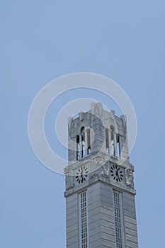 Close up grey Bell and clock tower up against blue clear sky.