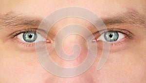 Close-up of the grey-blue eyes of a young man looking at the camera. Calm look of a confident person. Natural light. Focus on the