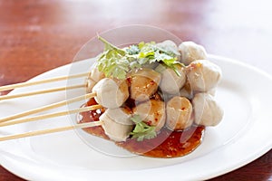 Close up Grilled pork balls with sweet spicy sauce on wooden table. P