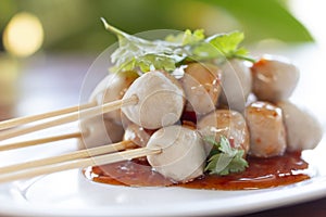 Close up Grilled pork balls with sweet spicy sauce on wooden table. P