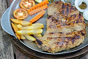 Close up of Grilled Pork Steaks and French Fries with Vegetable